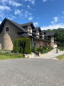 Front dworku z brukowanym podjazdem i różami