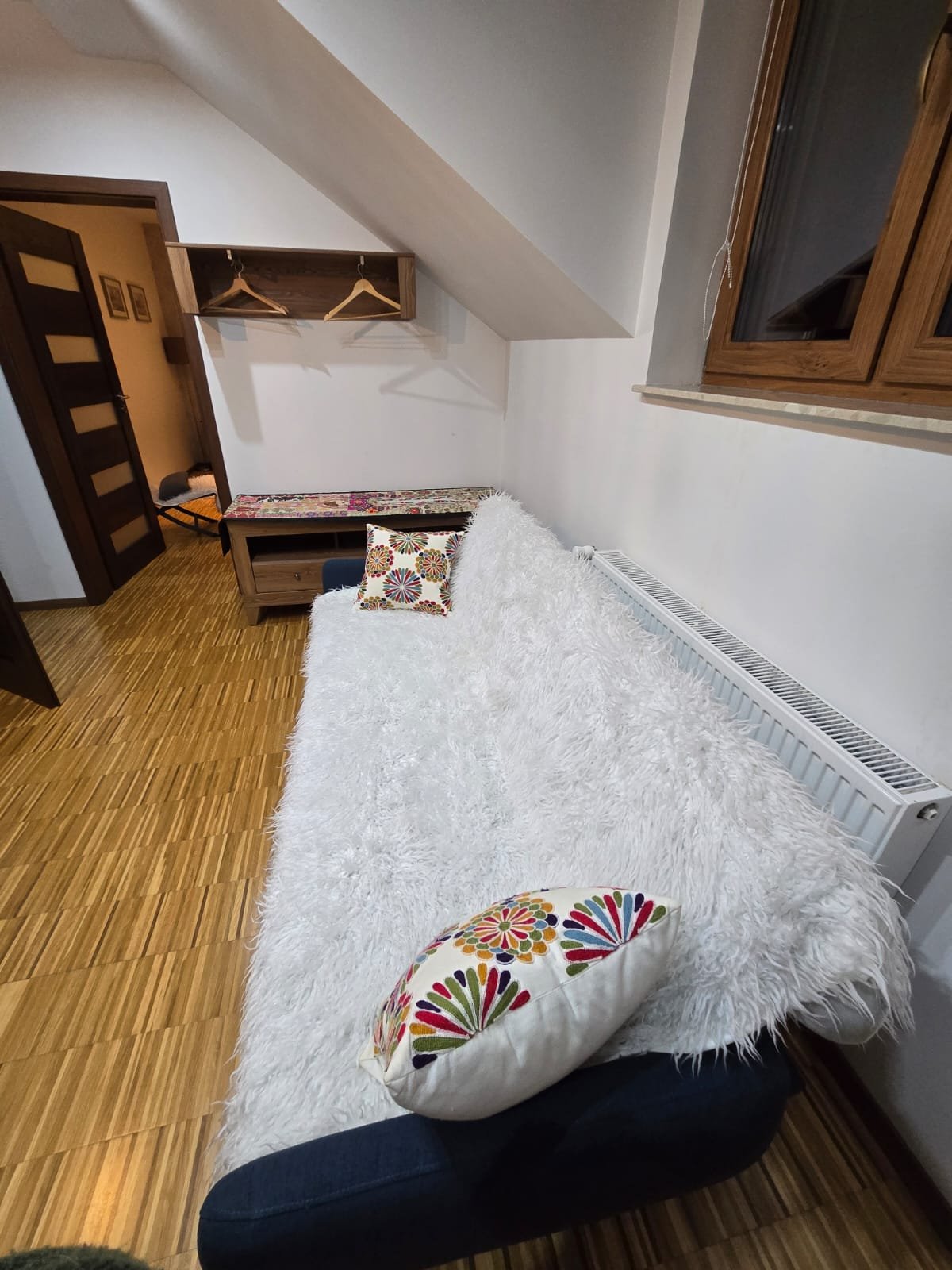 Pokój Triple z białą pościelą futrzastą i poduszkami z ludowym motywem