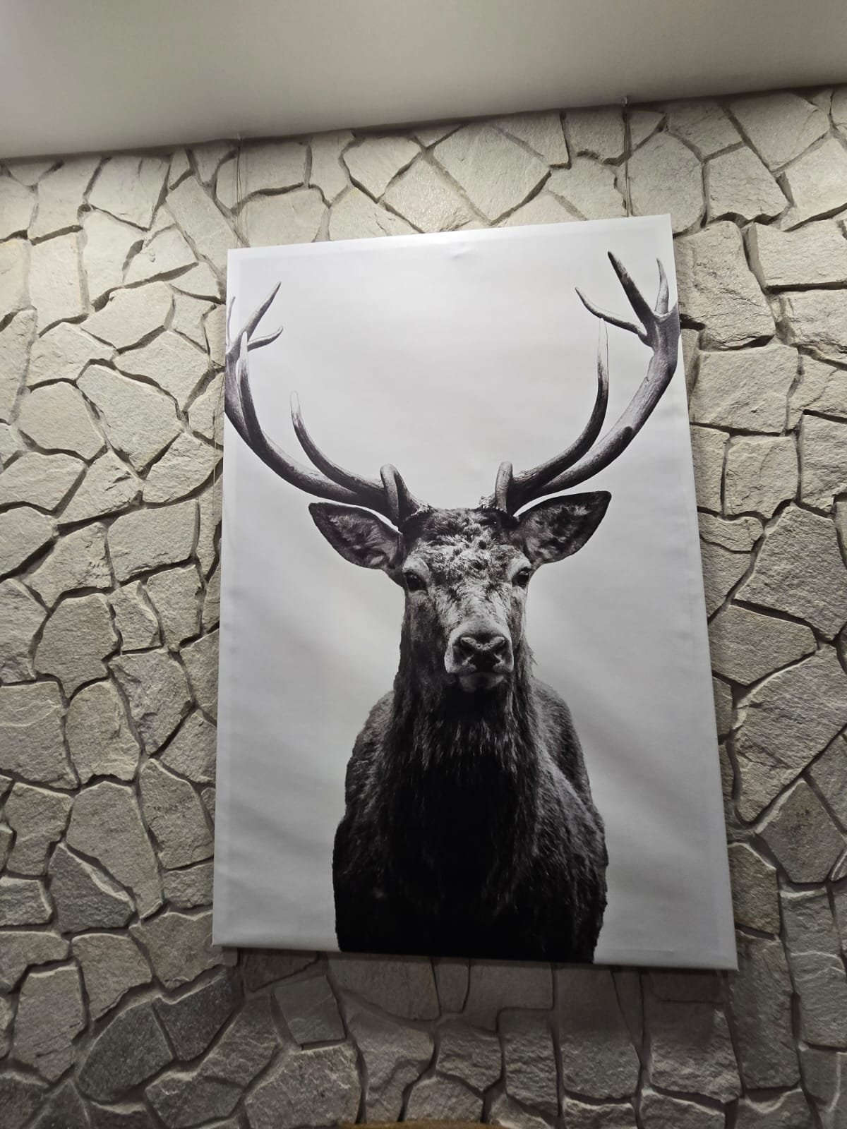 Detal dekoracyjny — obraz jelenia na tle kamiennej ściany